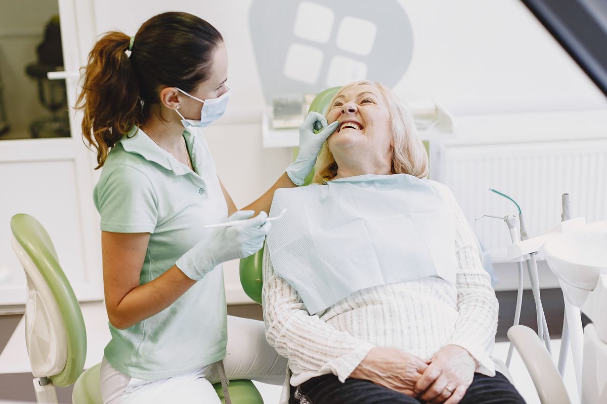 Starszy pacjent po wszczepieniu implantu zębowego w rozmowie z dentystą