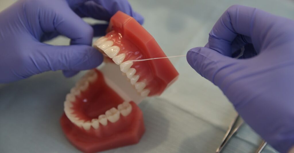 Szczoteczka międzyzębowa i nić dentystyczna prezentowane przy modelu zębów w klinice